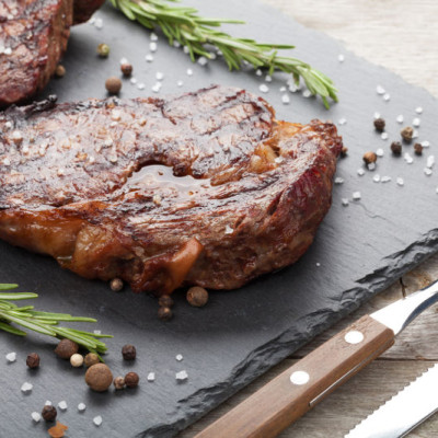Beef steaks with rosemary and spices on wooden table